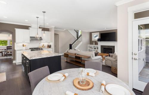 panorama of beautiful kitchen, living room, and eating nook in new luxury home with island, pendant lights, stainless steel appliances, and hardwood floors